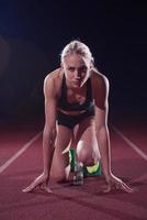 woman  sprinter leaving starting blocks photo