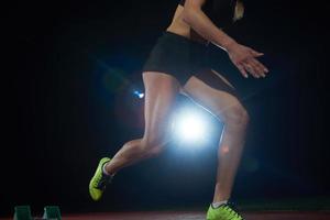 woman  sprinter leaving starting blocks photo