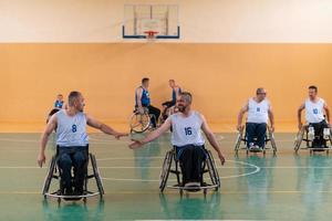 un equipo de veteranos de guerra en sillas de ruedas jugando baloncesto, celebrando los puntos ganados en un partido. choca esos cinco concepto foto