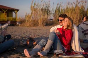 Couple enjoying with friends at sunset on the beach photo