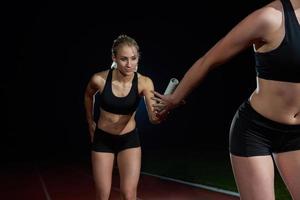 athletic runners passing baton in relay race photo