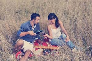 pareja feliz disfrutando de un picnic en el campo en hierba larga foto