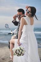 just married couple on the beach ride white scooter photo