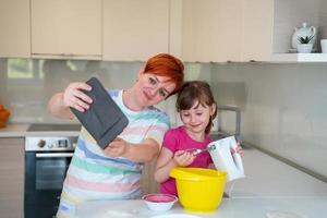 little girl and mom making tastz cake in kithen family having fun at home photo
