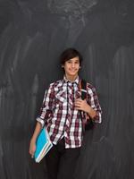 arab teenager with backpack wearing casual school look against black chalkboard background photo