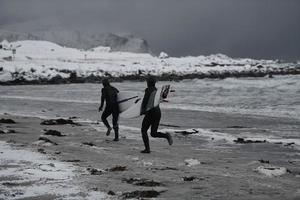 Arctic surfers running on  beach after surfing photo