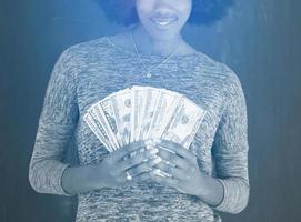 black woman holding money on gray background photo