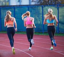 grupo de mujeres atletas corriendo en la pista de carreras de atletismo foto