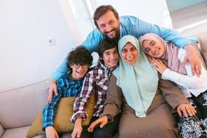 Portrait photo of an arab muslim family sitting on a couch in the living room of a large modern house. Selective focus
