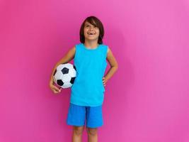 Portrait of young Arabic boy with soccer ball isolated against pink background and copy space photo