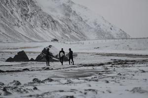 surfistas árticos que van por la playa después de surfear foto