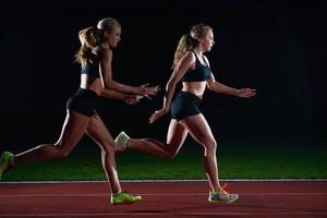 corredores atléticos que pasan la batuta en la carrera de relevos foto