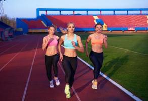 grupo de mujeres atletas corriendo en la pista de carreras de atletismo foto