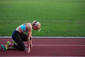 woman  sprinter leaving starting blocks photo