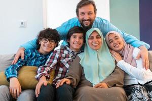 Portrait photo of an arab muslim family sitting on a couch in the living room of a large modern house. Selective focus