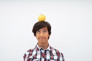 A funny portrait of a young attractive Arab boy with apple on his head isolated on a white background. Selective focus photo