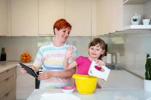 little girl and mom making tastz cake in kithen family having fun at home photo