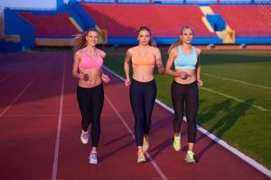 grupo de mujeres atletas corriendo en la pista de carreras de atletismo foto