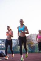 grupo de mujeres atletas corriendo en la pista de carreras de atletismo foto