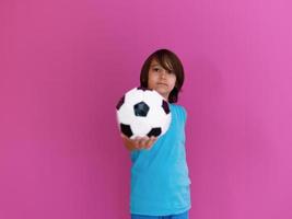 Portrait of young Arabic boy with soccer ball isolated against pink background and copy space photo