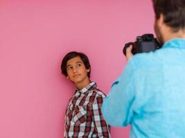 A photo of a father and son taking family photos in the house in front of a purple wall. Selective focus