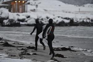 Arctic surfers running on  beach after surfing photo