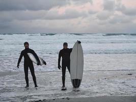 Arctic surfers going by beach after surfing photo