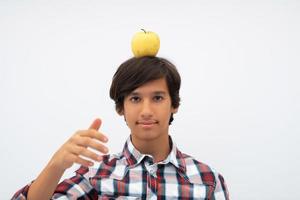 A funny portrait of a young attractive Arab boy with apple on his head isolated on a white background. Selective focus photo