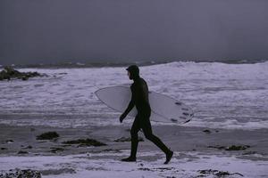 surfista ártico yendo por la playa después de surfear foto