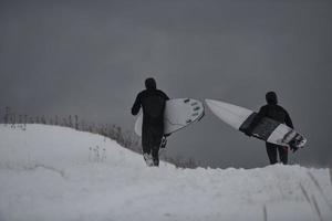 Arctic surfers running on  beach after surfing photo