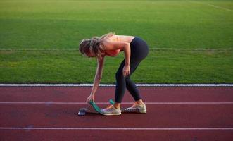 woman  sprinter leaving starting blocks photo