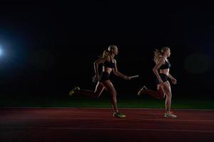 athletic runners passing baton in relay race photo