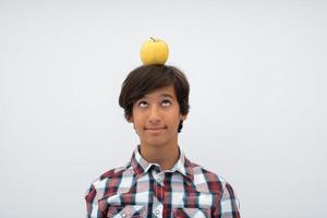 A funny portrait of a young attractive Arab boy with apple on his head isolated on a white background. Selective focus photo