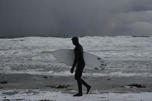 surfista ártico yendo por la playa después de surfear foto