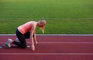 woman  sprinter leaving starting blocks photo