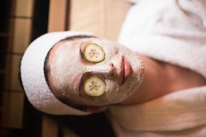 woman is getting facial clay mask at spa photo