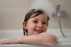 little girl in bath playing with foam photo
