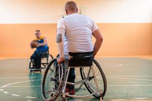 Disabled War veterans mixed race and age basketball teams in wheelchairs playing a training match in a sports gym hall. Handicapped people rehabilitation and inclusion concept photo