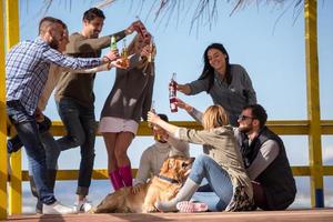 grupo de amigos divirtiéndose el día de otoño en la playa foto