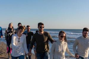 Group of friends running on beach during autumn day photo