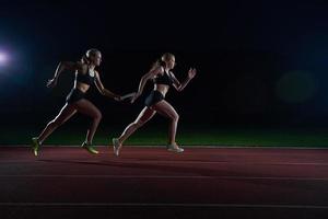 corredores atléticos que pasan la batuta en la carrera de relevos foto