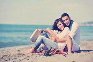 pareja joven disfrutando de un picnic en la playa foto