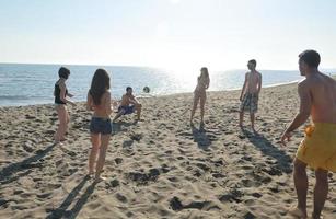 grupo de jóvenes divertirse y jugar voleibol de playa foto