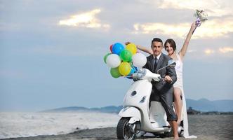 just married couple on the beach ride white scooter photo