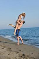 feliz pareja joven tiene tiempo romántico en la playa foto