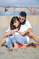 pareja joven disfrutando de un picnic en la playa foto