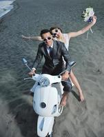 just married couple on the beach ride white scooter photo