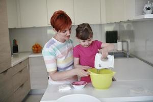 madre e hija jugando y preparando masa en la cocina. foto