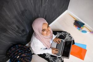 arab female student working on laptop from home top view photo