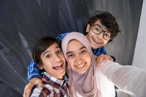 grupo de adolescentes árabes tomando una foto selfie en un teléfono inteligente con pizarra negra en el fondo. enfoque selectivo